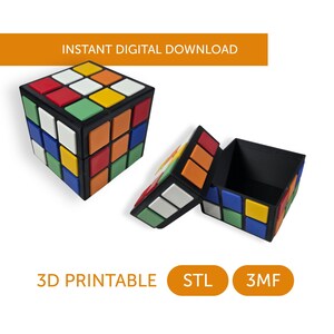 May include: A black cube-shaped storage box with a lid designed to resemble a multi-colored puzzle cube featuring red, blue, green, yellow, and white square tiles. The text INSTANT DIGITAL DOWNLOAD, 3D PRINTABLE, STL, and 3MF are visible.