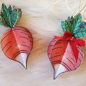 May include: Two red and white Christmas ornaments shaped like radishes with green tops and gold string hangers. One ornament has a red bow.