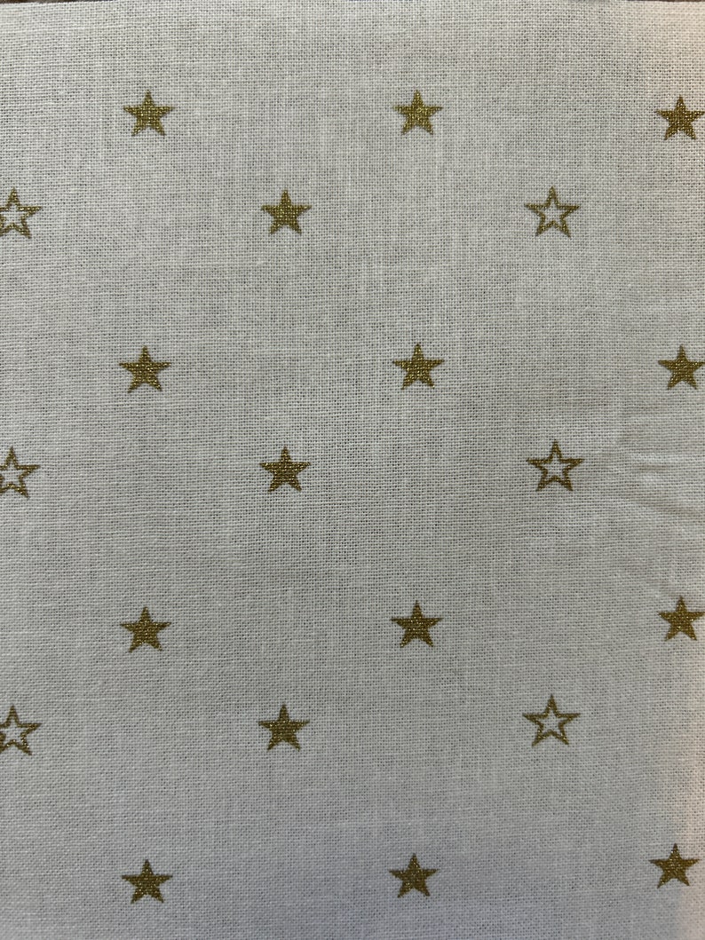May include: White fabric with a subtle texture, featuring a repeating pattern of gold stars.