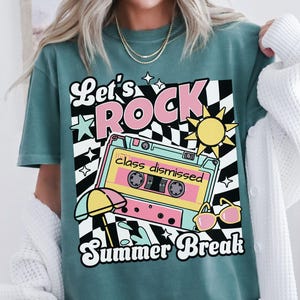 May include: Seafoam green t-shirt with a retro graphic design. The design features the words "Let's ROCK" in pink and white, a cassette tape with "class dismissed", a sun, sunglasses, and the words "Summer Break".