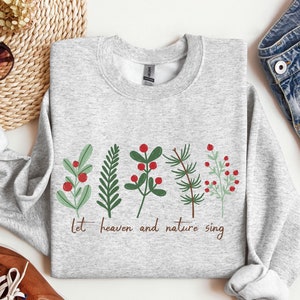 May include: Gray sweatshirt with a Christmas-themed design featuring green sprigs with red berries and the text "Let heaven and nature sing".