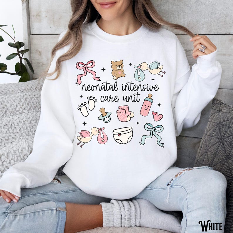 Op de afbeelding: Wit sweatshirt met een grafisch ontwerp van babygerelateerde iconen en de tekst "neonatal intensive care unit".