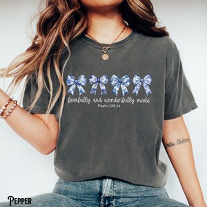 以下が含まれることがあります： 青と白のリボンが並んだダークグレーのTシャツ。Tシャツには「fearfully and wonderfully made」と「Psalm 139:14」の文字がプリントされています。
