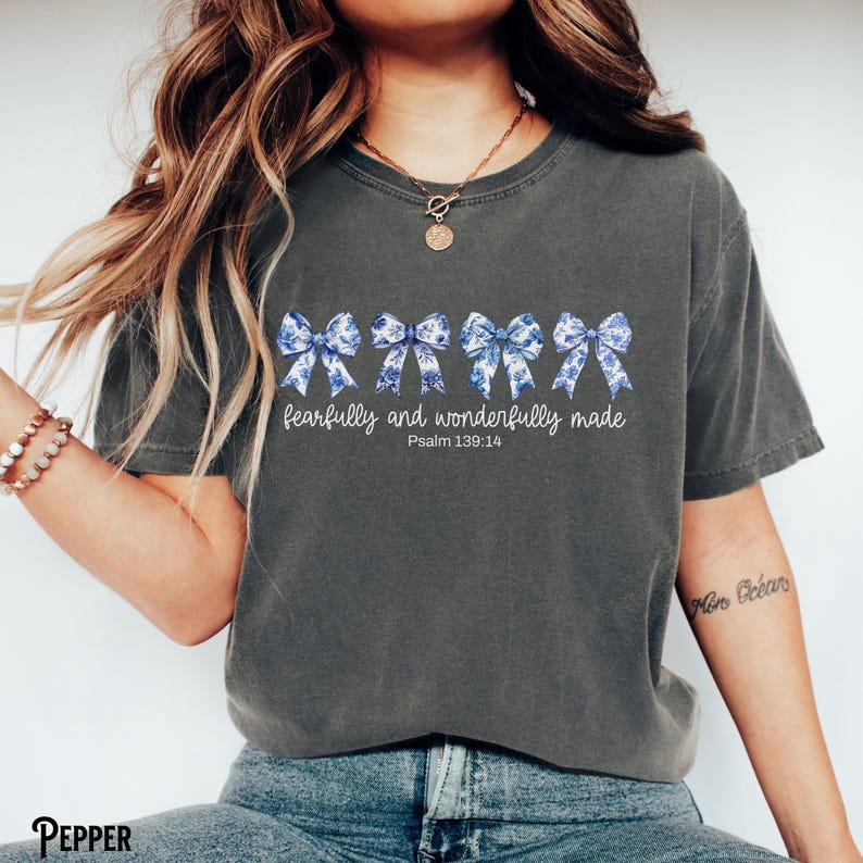 以下が含まれることがあります： 青と白のリボンが並んだダークグレーのTシャツ。Tシャツには「fearfully and wonderfully made」と「Psalm 139:14」の文字がプリントされています。