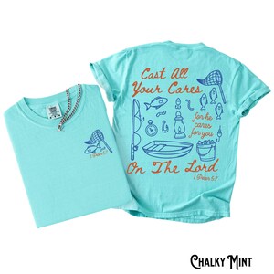 K&ouml;nnte beinhalten: Zwei hellblaue T-Shirts mit Angelmotiven. Ein Shirt hat eine kleine Grafik auf der Brust und eine Halskette. Das andere Shirt hat ein gr&ouml;&szlig;eres Design auf dem R&uuml;cken mit dem Text "Cast All Your Cares On The Lord" und Illustrationen zum Thema Angeln.