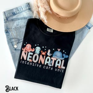 May include: Black t-shirt featuring a graphic of sea creatures and the text "NEONATAL intensive care unit".