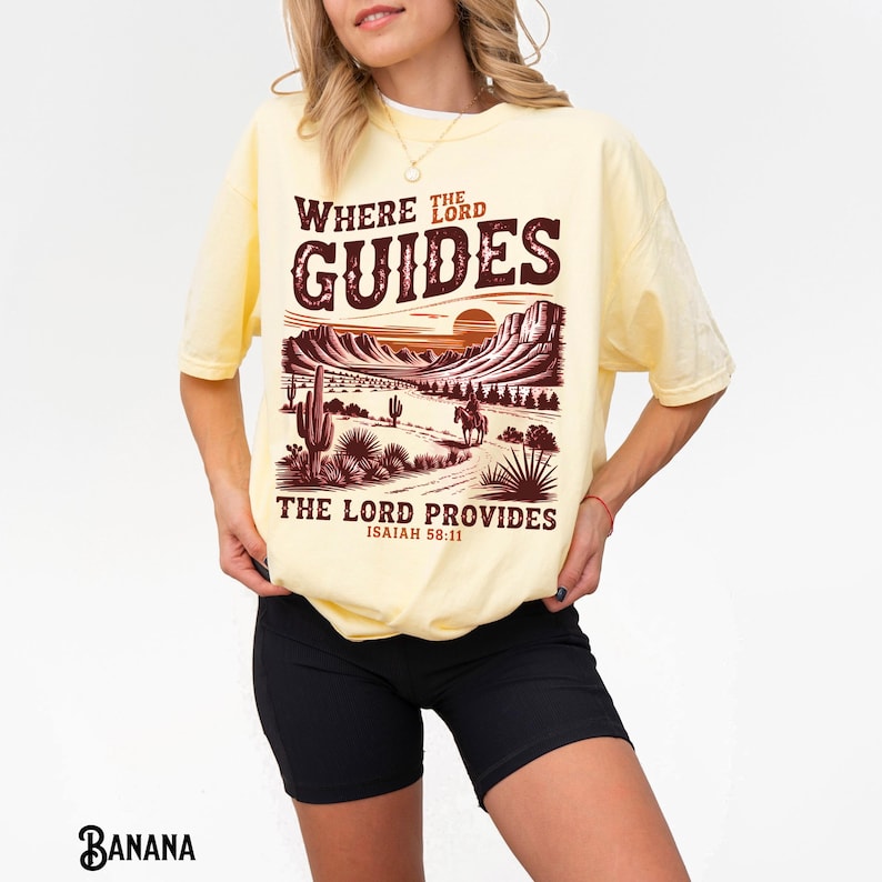 May include: A yellow t-shirt with a graphic print of a desert landscape with a sunset and the text "Where the Lord Guides, The Lord Provides, Isaiah 58:11".