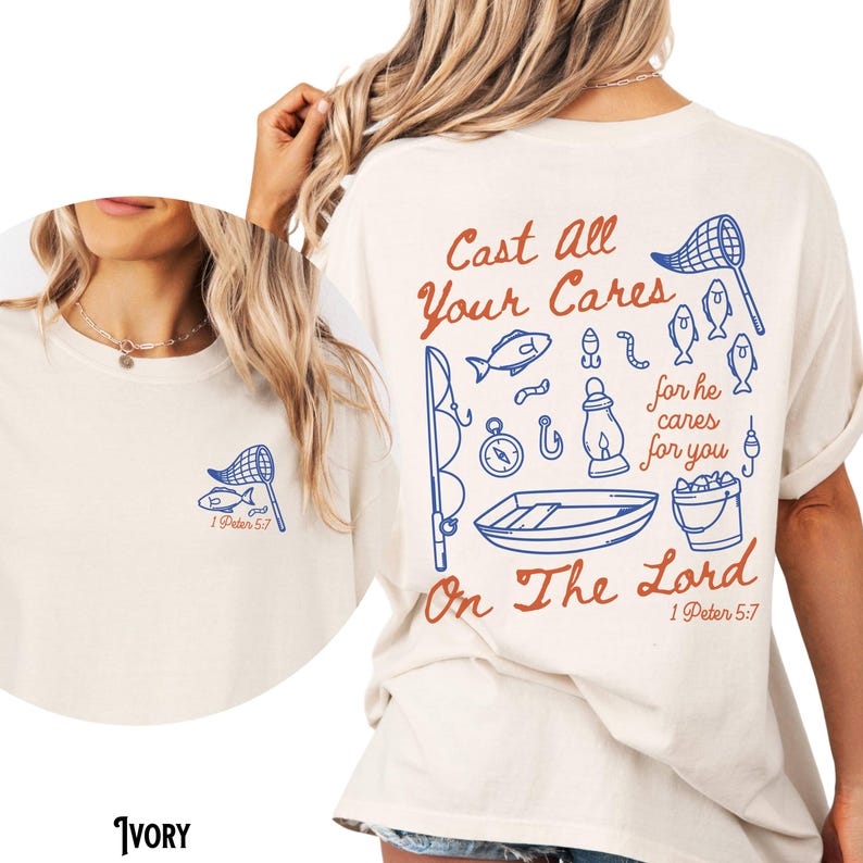 May include: Ivory-colored t-shirt with a fishing-themed graphic in blue and red. The design includes a fishing net, fish, and the text "Cast All Your Cares On The Lord" from 1 Peter 5:7. The shirt is a casual, comfortable style.