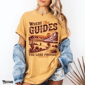 May include: A mustard yellow t-shirt with a graphic of a desert landscape and the text "Where the Lord Guides, The Lord Provides, Isaiah 58:11".