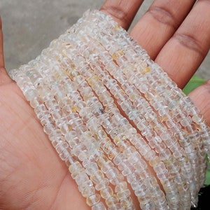 May include: A strand of clear, faceted, square-shaped beads. The beads are translucent and have a slight yellow tint. The beads are strung on a clear thread.