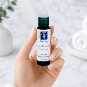 May include: Aroma roll-on bottle with a clear rollerball top and a dark green base. The label reads "Prodigy I Am Rested Aroma Roll" and "OmVeLaGe Relaxing Support Blend". The bottle contains 0.34 fl oz (10ml).