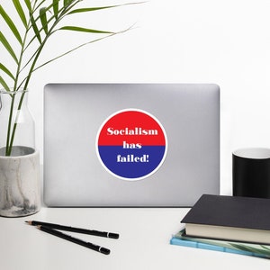 Może przedstawiać: Okrągła naklejka w kolorze czerwonym i niebieskim z napisem "Socialism has failed!" w kolorze białym.
