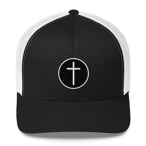 May include: Black and white trucker hat with a white circle and cross design. The hat has a black front and a white mesh back.