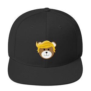 Könnte beinhalten: Schwarze und gelbe bestickte Baseballkappe mit einem Cartoon-Teddybär, der eine blonde Perücke trägt.