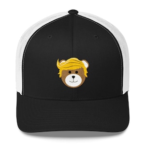 May include: Black and white trucker hat with a brown teddy bear wearing a yellow wig. The teddy bear has a white smile and white eyes.