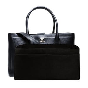 May include: Black leather tote bag with top handles and a shoulder strap. The bag features a silver-tone logo and is paired with a black felt organiser insert. The tote bag is designed for carrying essentials.