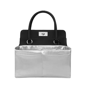 Puede incluir: Bolso de mano negro con un organizador interior plateado. El bolso tiene un asa superior y un cierre plateado. El organizador interior tiene múltiples compartimentos para guardar cosas. El bolso está diseñado para mantener los artículos organizados.