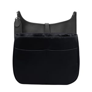 May include: A black handbag organizer with two front pockets, designed to fit inside a larger bag. The organizer is made of a smooth, dark material. The outer bag is a dark gray, crescent-shaped shoulder bag.