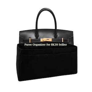 Puede incluir: Un organizador de bolsos de fieltro negro para BK30 Sellier colocado frente a un bolso de cuero negro con herrajes dorados. El texto "Purse Organizer for BK30 Sellier" está impreso en blanco en el frente del inserto rectangular de fieltro.