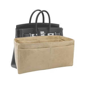 May include: Beige felt handbag organiser with multiple compartments and pockets. The organiser is designed to fit inside a larger handbag.