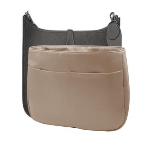 May include: A dark gray leather handbag with a matching strap and a beige interior organizer. The organizer has two pockets and is designed to fit inside the handbag. The handbag has a buckle closure.