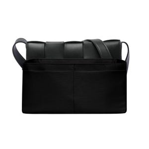 Könnte beinhalten: Schwarze Umhängetasche mit gewebter oberer Klappe und langem, verstellbarem Riemen. Die Tasche hat eine rechteckige Form mit strukturiertem Design und einer Vordertasche. Der Innenraum hat mehrere Fächer.