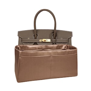 May include: A brown satin bag organizer with multiple compartments and pockets. The organizer is designed to fit inside a handbag.