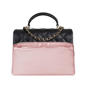 May include: A black quilted handbag with a gold chain strap and a pink satin lining. The bag has a top handle and a flap closure.