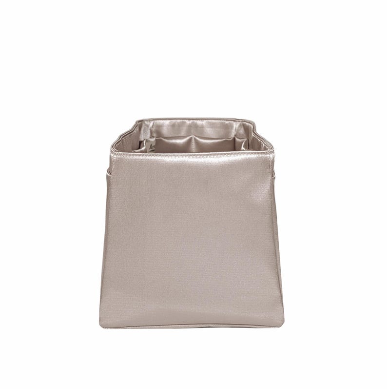 Puede incluir: Una bolsa rectangular plateada met&aacute;lica con interior de sat&eacute;n. La bolsa tiene una forma estructurada con una abertura ligeramente ensanchada. El interior es de un tono plateado m&aacute;s claro, creando un contraste. La bolsa probablemente est&aacute; dise&ntilde;ada para guardar o transportar objetos peque&ntilde;os.