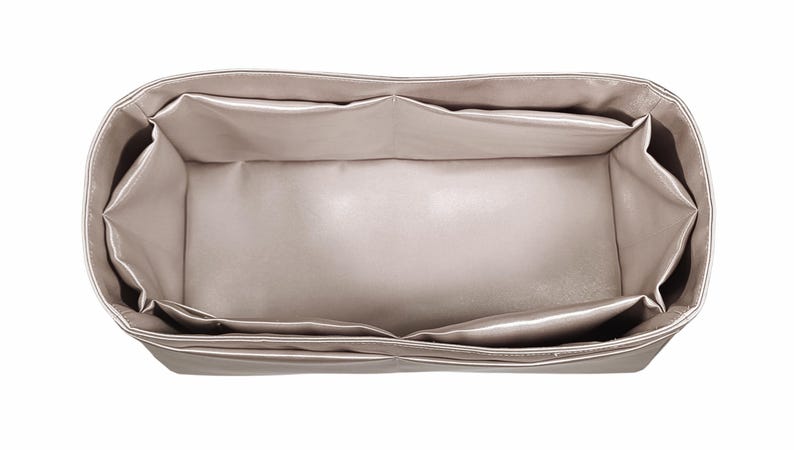 Puede incluir: Un organizador de bolso beige con m&uacute;ltiples compartimentos. El organizador es rectangular con un dise&ntilde;o estructurado, con varios bolsillos interiores para la organizaci&oacute;n. El material parece ser una tela lisa, posiblemente satinada, de color neutro.