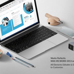 May include: A laptop computer displaying a Microsoft Word document with a brochure template. The document has a blue and gray color scheme and features a cityscape graphic. The text "Brochure Template" is visible on the document. The laptop is on a white surface with a pencil holder, a smartphone, and a smartwatch.