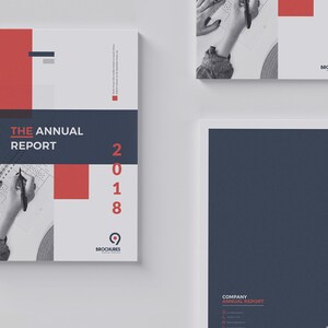 K&ouml;nnte beinhalten: Ein wei&szlig;er und grauer Jahresbericht-Umschlag mit einem roten und blauen Design. Der Umschlag zeigt den Text "THE ANNUAL REPORT" und das Jahr "2018". Der Umschlag enth&auml;lt auch ein kleines Logo mit dem Text "BROCHURES".