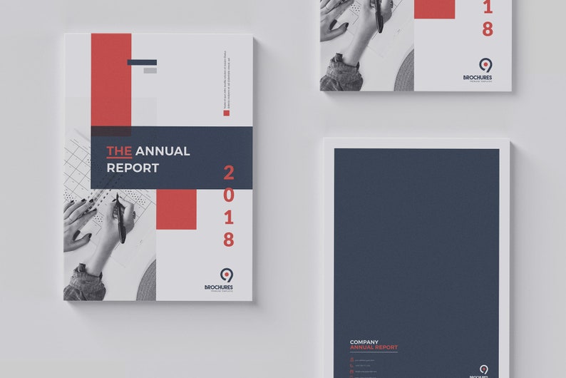 K&ouml;nnte beinhalten: Ein wei&szlig;er und grauer Jahresbericht-Umschlag mit einem roten und blauen Design. Der Umschlag zeigt den Text "THE ANNUAL REPORT" und das Jahr "2018". Der Umschlag enth&auml;lt auch ein kleines Logo mit dem Text "BROCHURES".