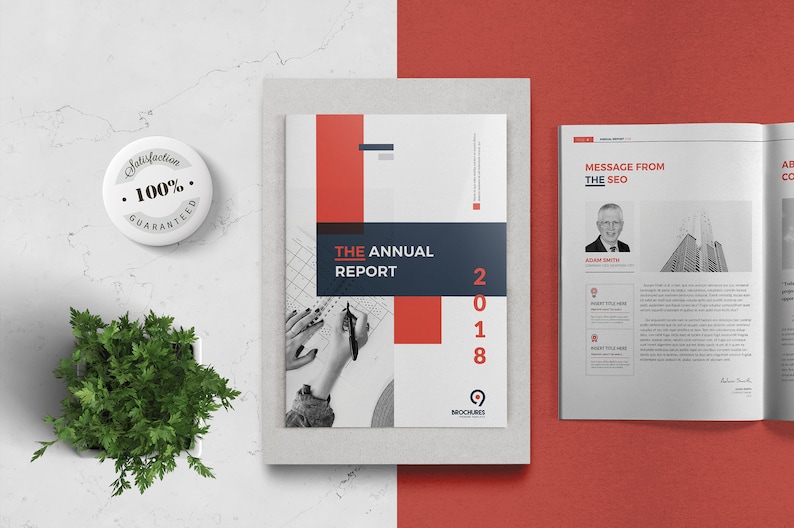 K&ouml;nnte beinhalten: Ein wei&szlig;er und roter Jahresbericht-Umschlag mit dem Text "THE ANNUAL REPORT 2018" und einem Schwarzwei&szlig;foto von H&auml;nden, die auf einem Raster schreiben.