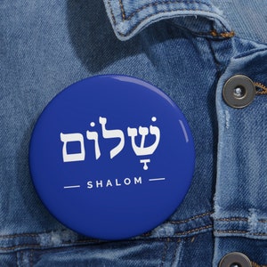 May include: A blue button with the Hebrew word for peace, "Shalom", written in white letters. The word "Shalom" is also written in English below the Hebrew word.