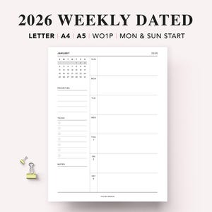 Può includere: Un'agenda settimanale bianca datata 2026 con un calendario di gennaio, una sezione priorità, una lista di cose da fare e una sezione note. L'agenda include il testo "2026 WEEKLY DATED" e "LETTER A4 A5 WO1P MON & SUN START". Due piccole clip gialle sono nell'angolo in basso a sinistra.