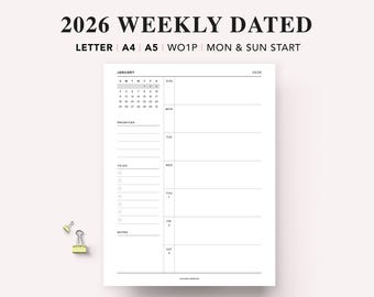 May include: A white 2026 weekly dated planner with a January calendar, priorities section, to-do list, and notes section. The planner includes the text "2026 WEEKLY DATED" and "LETTER A4 A5 WO1P MON & SUN START". Two small yellow binder clips are in the lower left corner.