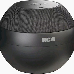 May include: A spherical black RCA wireless speaker featuring a textured fabric top section and a smooth matte finish lower body. The top panel includes integrated control buttons for power, volume, and mode selection, with the RCA logo printed in white.