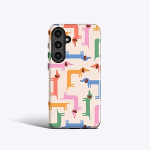 May include: A phone case featuring a repeating pattern of colorful dachshund dogs in various poses. The dogs are in shades of pink, orange, blue, green, and yellow against a light beige background. The case has a camera module on the upper left.