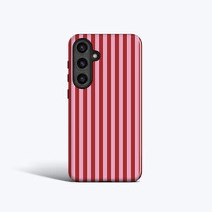May include: A red and pink striped phone case with a black camera lens.