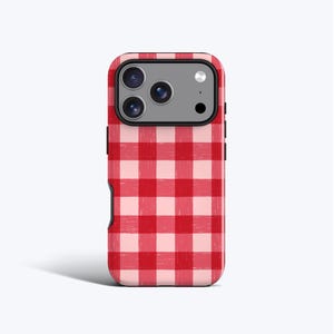 Puede incluir: Una funda para teléfono con estampado de cuadros rojos y blancos. La funda tiene forma rectangular con esquinas redondeadas y un recorte para la cámara. La funda está diseñada para adaptarse a un teléfono inteligente y tiene una ranura para tarjetas.