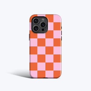 Può includere: Una custodia per telefono con un motivo a scacchiera rosa e arancione. La custodia ha una finitura lucida e un ritaglio per la fotocamera sul retro. La custodia è progettata per adattarsi a uno smartphone.