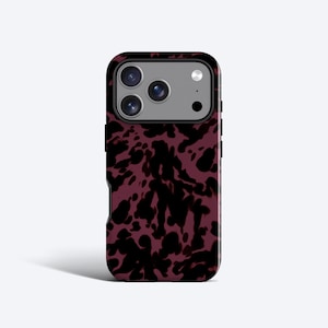 May include: A smartphone case featuring a dark burgundy and black abstract mottled pattern. The case has a rectangular cutout at the top for a triple-lens camera system and a flash, with a grey camera module surround visible within the cutout.