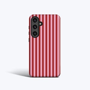 Può includere: Una custodia per smartphone con un motivo a righe verticali in tonalità rosse e rosa alternate. La custodia ha un modulo fotocamera nero sul lato superiore sinistro.