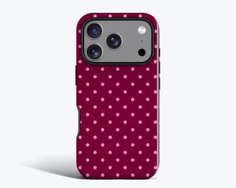Puede incluir: Una funda para smartphone con un fondo de color burdeos intenso y un patrón repetitivo de pequeños lunares de color rosa claro. La funda incluye un recorte rectangular en la parte superior para un sistema de triple cámara y flash, con un borde negro.
