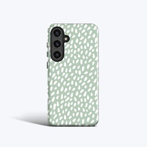 May include: A pale green phone case featuring a repeating pattern of white, oval-shaped spots. The case has a black camera module and buttons on the side. The design is minimalist and contemporary.