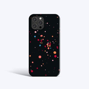 Puede incluir: Funda de teléfono negra con un diseño de salpicaduras de colores. La funda presenta un patrón de puntos rojos, naranjas, rosas y azules. La funda del teléfono tiene un recorte para la cámara y un acabado brillante.