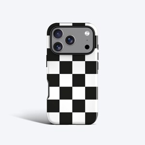 Può includere: Una custodia per smartphone con un motivo a scacchi in bianco e nero. La custodia ha un ritaglio per la fotocamera e un design protettivo. La custodia è bianca con un motivo a scacchi neri.
