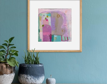 Op de afbeelding: Een ingelijst abstract schilderij met een roze, paarse en blauwe kleurstelling. Het schilderij is in een licht houten lijst en hangt aan een lichtblauwe muur.