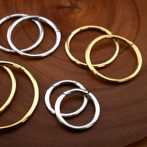 May include: A set of four hoop earrings in two different sizes. Two of the hoops are silver and two are gold.